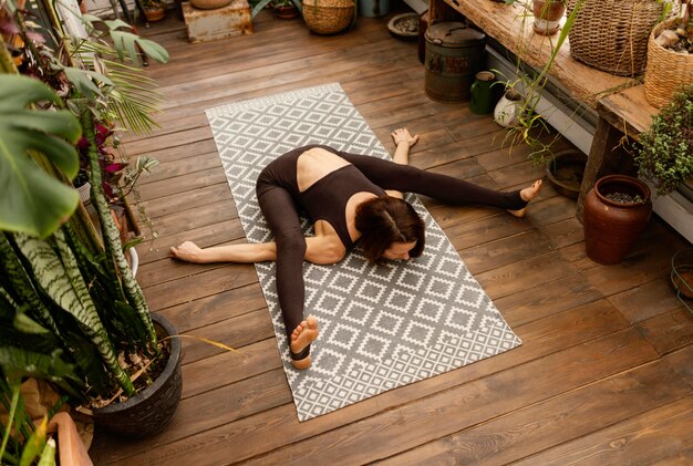 Full shot woman stretching on yoga mat