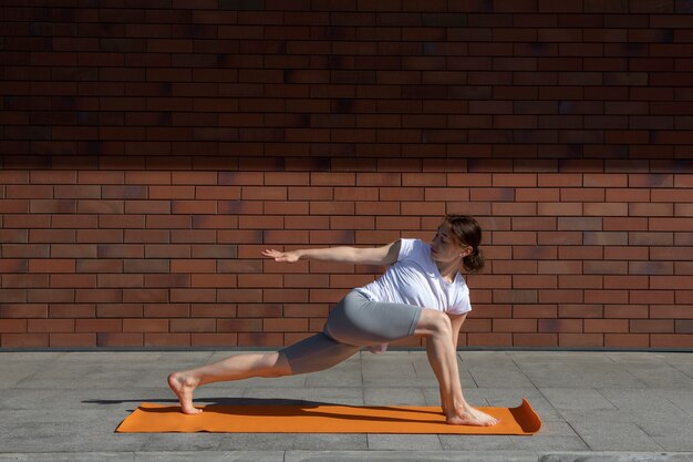 Full shot woman stretching on yoga mat