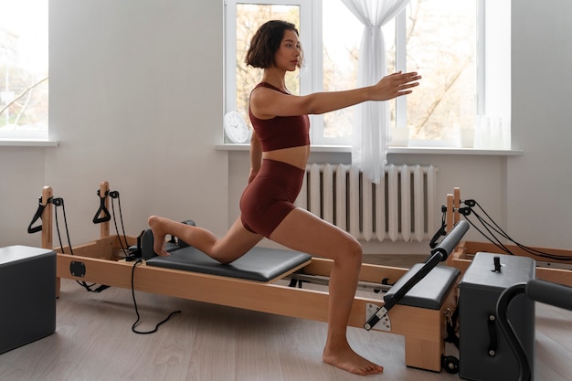 Free photo full shot woman taking  pilates reformer class