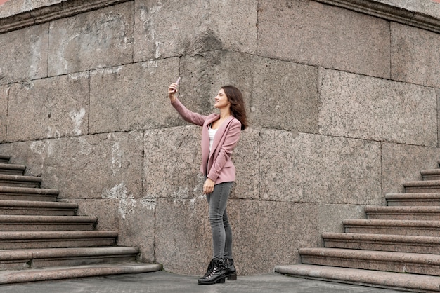 Free photo full shot woman taking selfie