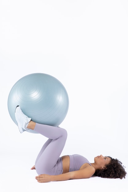 Free photo full shot woman training with gym ball