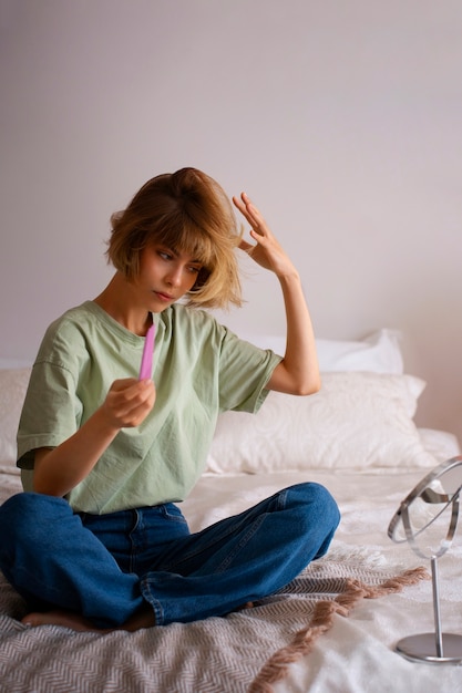 Full shot woman using dry shampoo at home