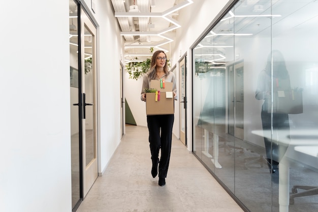 Free photo full shot woman walking with cardboard box