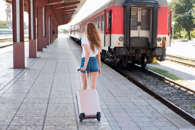 Full shot woman walking with luggage in train station