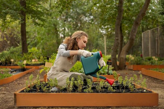 Full shot woman watering garden plants