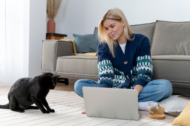 Full shot woman with cat at home