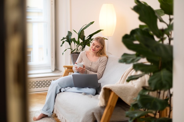 Free photo full shot woman with laptop on couch