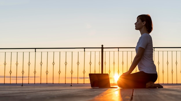 Full shot woman with laptop meditating