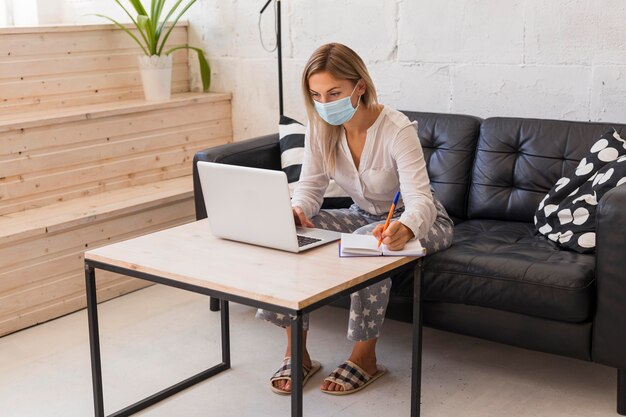 Full shot woman with mask and laptop