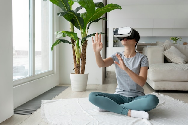 Free photo full shot woman with vr glasses on floor