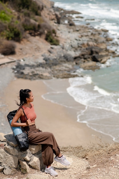 Full shot woman with yoga mat at beach