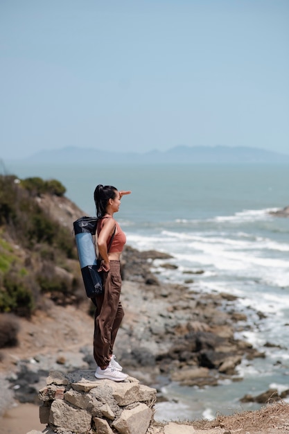 Full shot woman with yoga mat at seaside