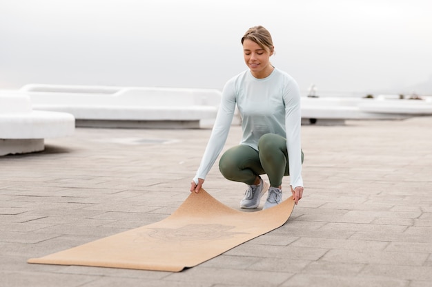 Full shot woman with yoga mat