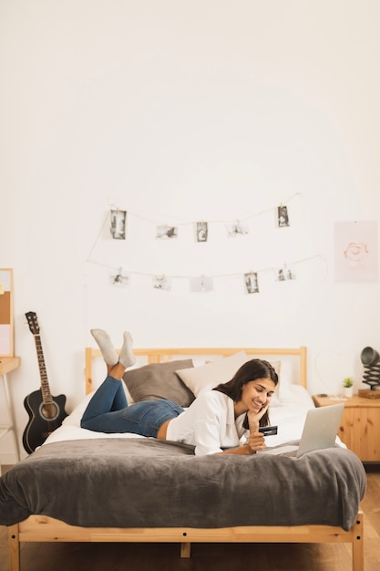 Free Photo full-shot woman working on laptop in bed