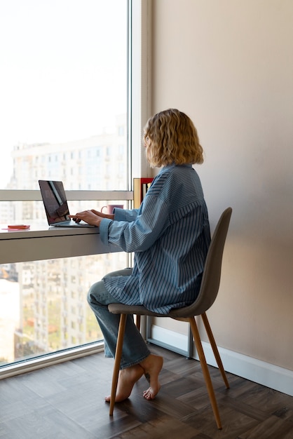 Free photo full shot woman working on laptop