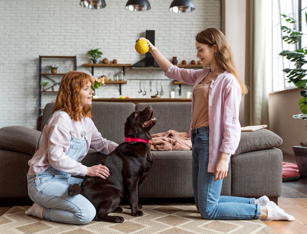 Free photo full shot women and dog with ball