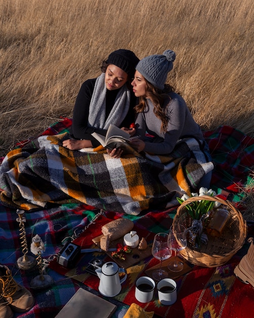 Free photo full shot women laying on blanket outdoors