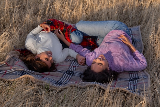 Free photo full shot women laying on blanket outdoors