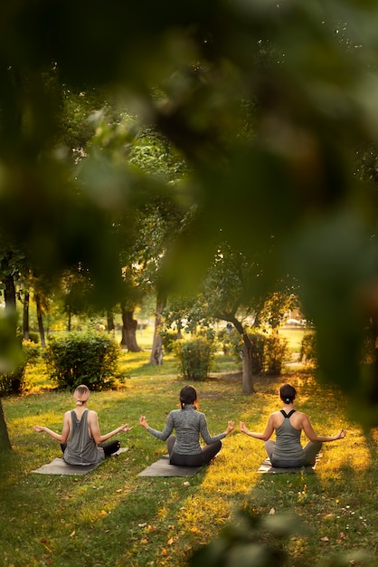 Free photo full shot women meditating outdoors