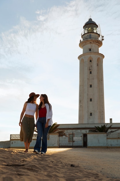 Free photo full shot women posing with lighthouse