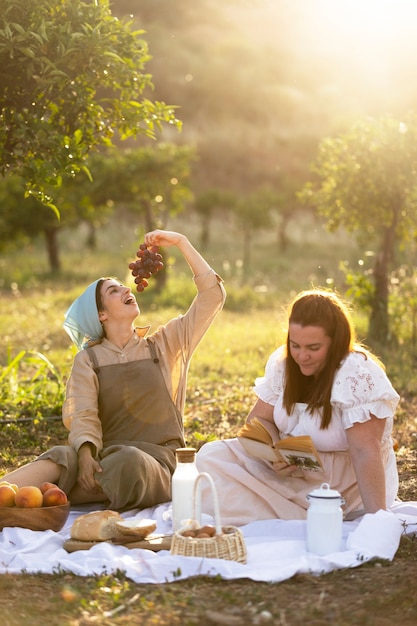 Free photo full shot women sitting together at picnic