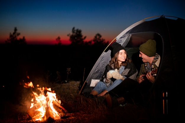 Full shot young couple warming up at night