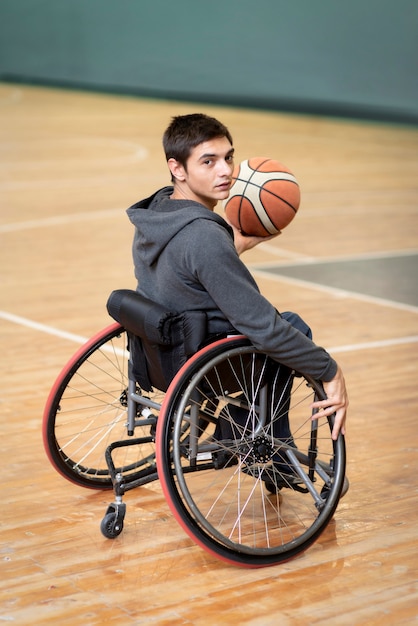 Full shot young disabled man holding ball