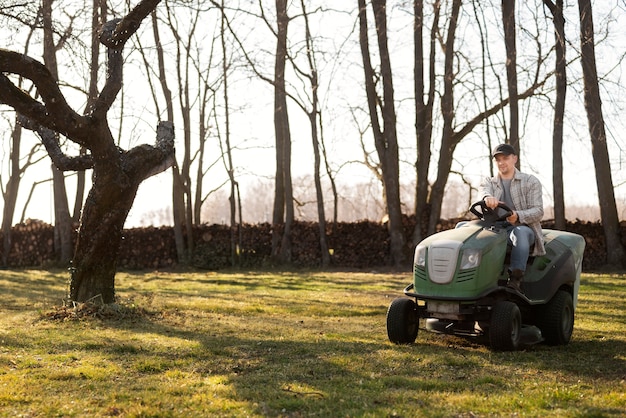 Free photo full shot young man driving lawn mower