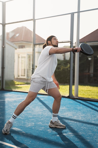 Full shot young man playing paddle tennis