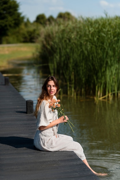 Free photo full shot young woman holding flowers