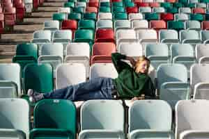 Free photo full shot young woman sitting on grandstands