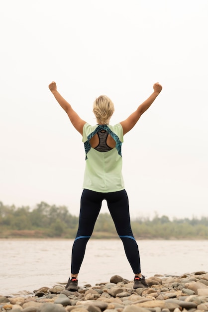 Full shot of a young woman with her arms in the air