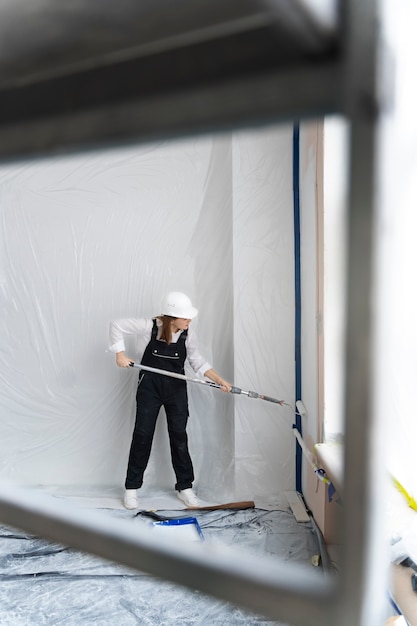 Free photo full shot young woman working with paint roller