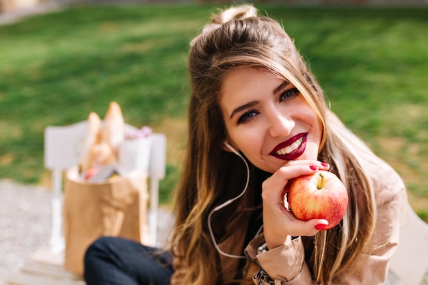 Free photo full-up portrait of lovely girl propped her face with hand and looks with interest after buying food.