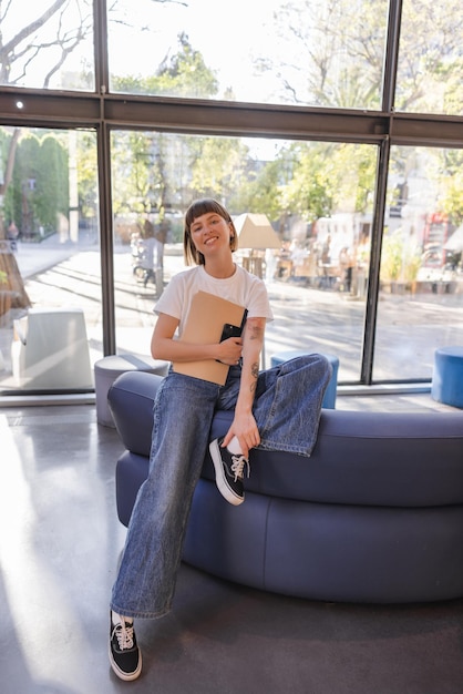 Free photo full view of stylish woman staying in cafe with notebooks