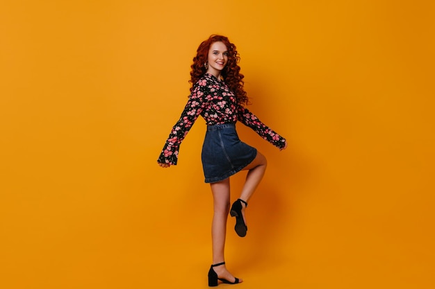 Free photo fulllength portrait of young woman in black sandals on city heel whirling in blue skirt and blouse on isolated background