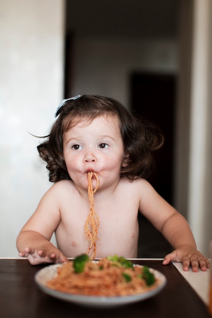 Funny baby girl eating spaghetti