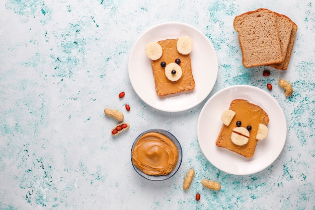 Funny bear and monkey face sandwich with peanut butter, banana and black currant, top view