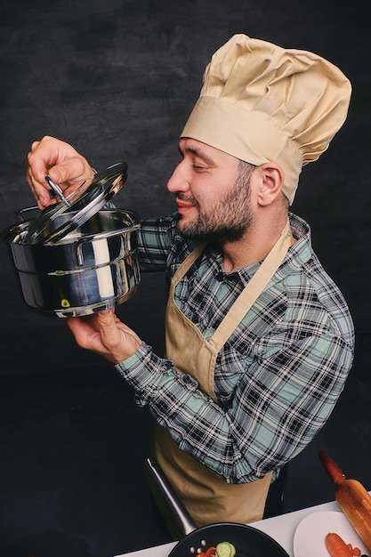 Funny bearded chef cook tasting the soup from a pan.