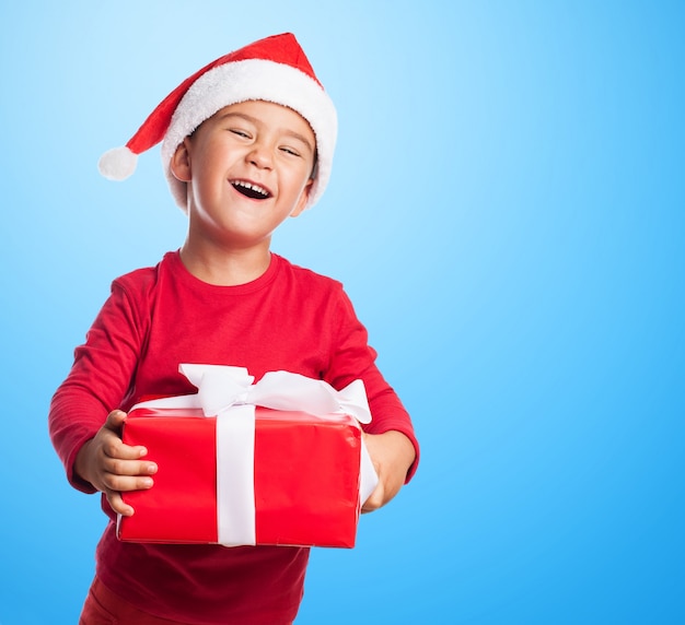 Funny boy holding a red gift with blue background