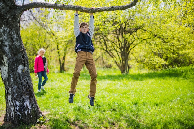 Funny boy playing on a tree branch