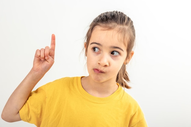 Free photo funny caucasian girl in yellow tshirt show finger up on a white background