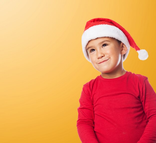 Funny child wearing santa hat with orange background