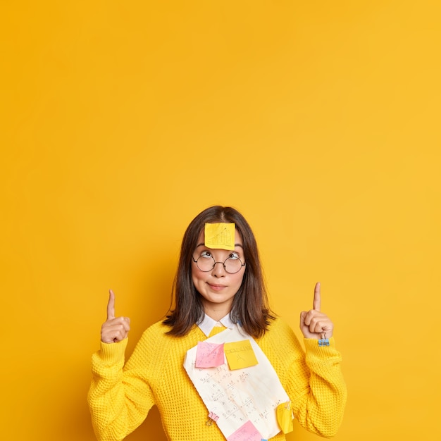 Free Photo funny crazy female student crosses eyes makes grimace tired, pointing at copy space