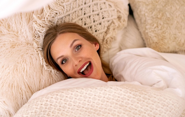 Funny cute morning portrait of blonde woman just woke up boho style bedroom Happy positive face