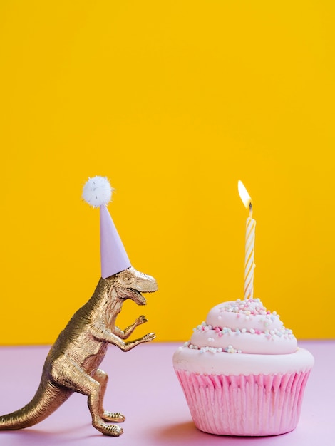 Free photo funny dinosaur with birthday hat and delicious muffin