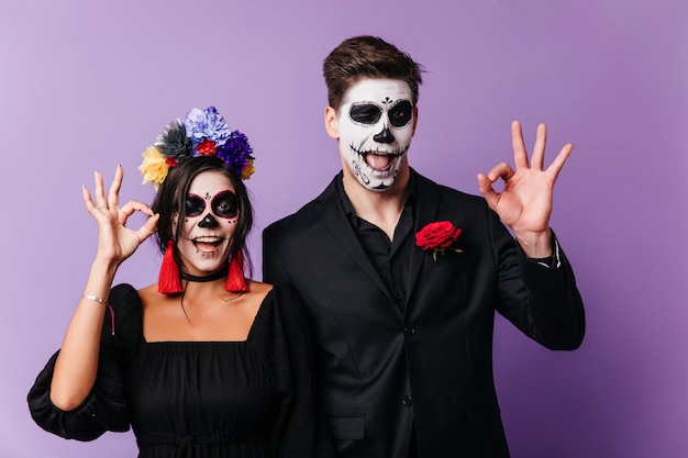 Funny european young people fooling around in halloween. Indoor shot of laughing loving couple in zombie attires.