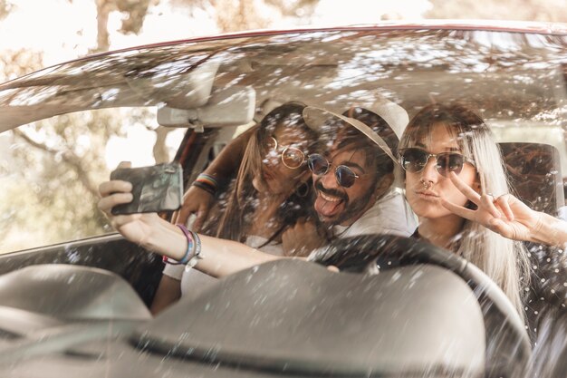 Funny friends taking selfie inside the car on mobile phone