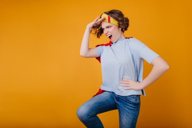 Funny girl in paper yellow crown fooling around on photoshoot