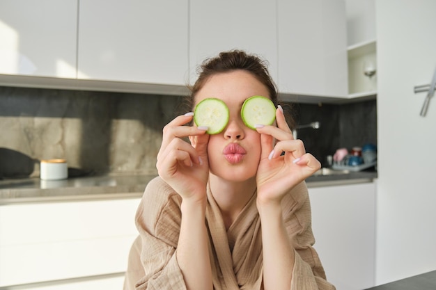 Free photo funny happy girl eating healthy holding zucchini chopping vegetables for healthy meal in the kitchen